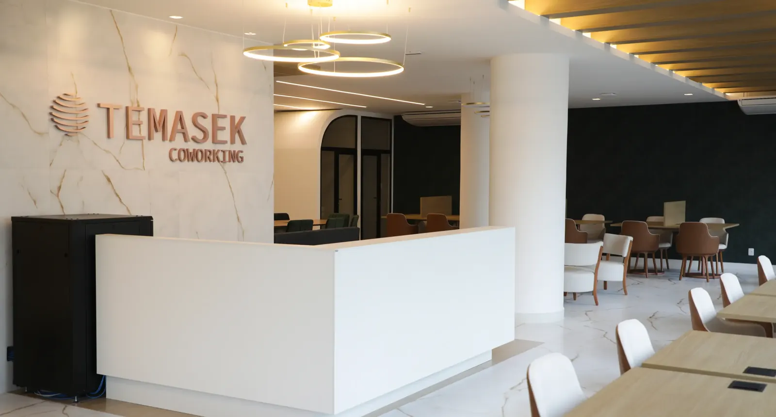 Recepção do Temasek Coworking, com logo em relevo na parede de mármore